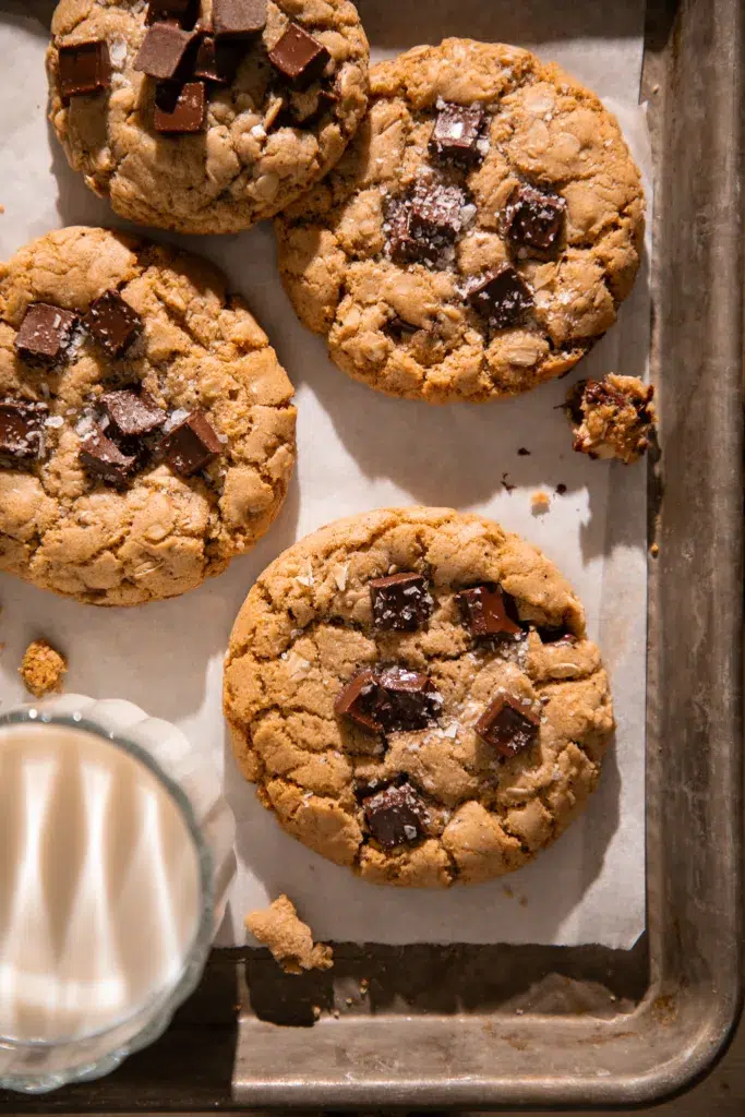 Tray of brown butter espresso oatmeal chocolate chunk cookies showing cracked tops, oats, and large chocolate chunks.