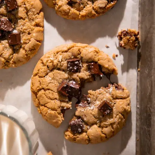 Close up of a brown butter espresso oatmeal chocolate chunk cookie with melty chocolate pools and flaky sea salt on top.