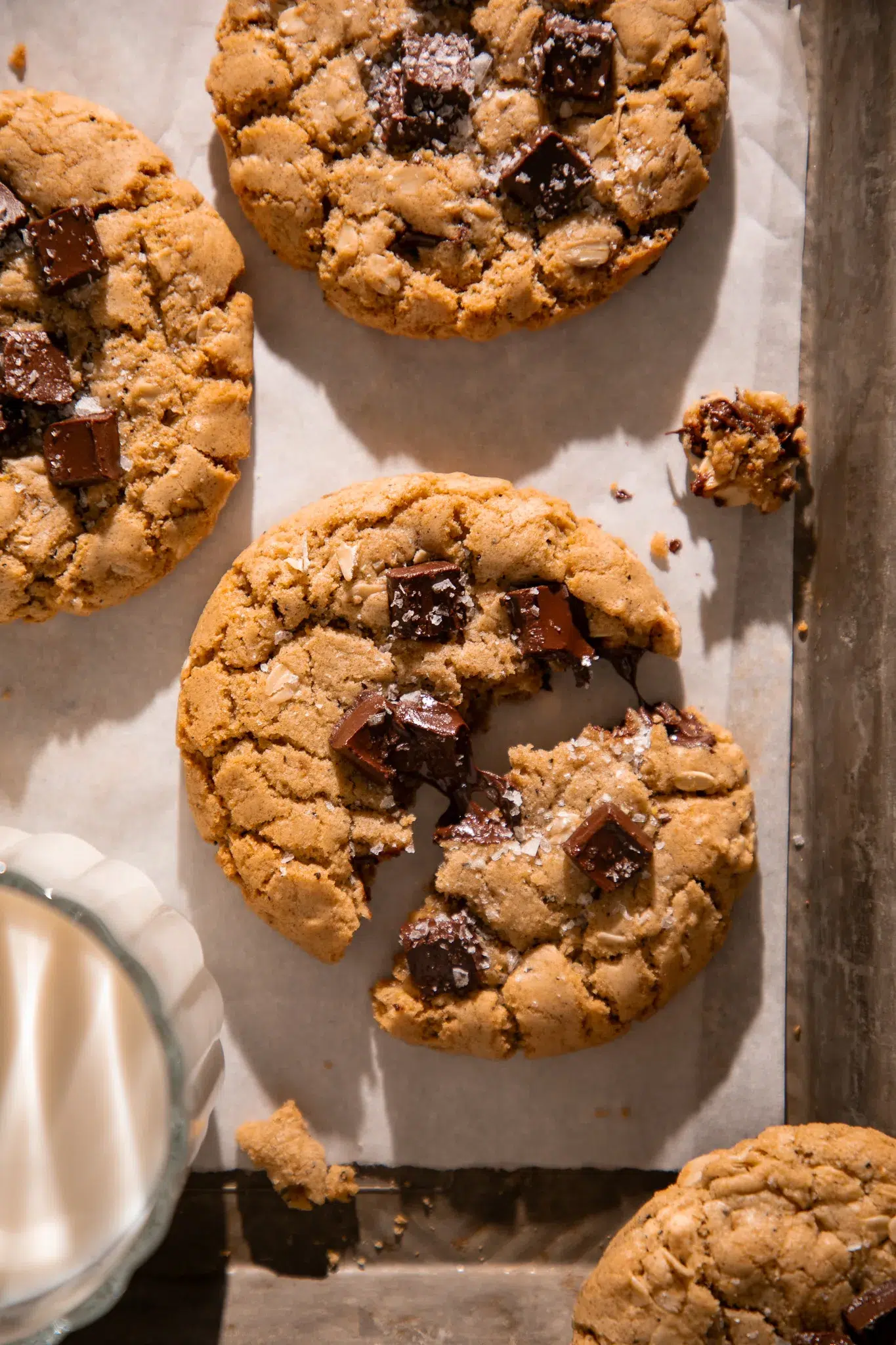 Close up of a brown butter espresso oatmeal chocolate chunk cookie with melty chocolate pools and flaky sea salt on top.