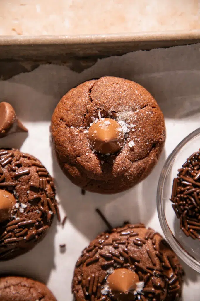 Close-up of a double chocolate blossom cookie topped with a chocolate kiss and flaky sea salt.