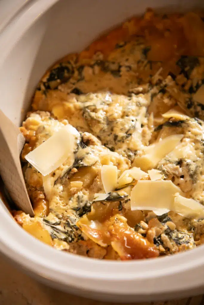 Close-up of creamy slow cooker white chicken lasagna topped with shaved cheese and red pepper flakes.