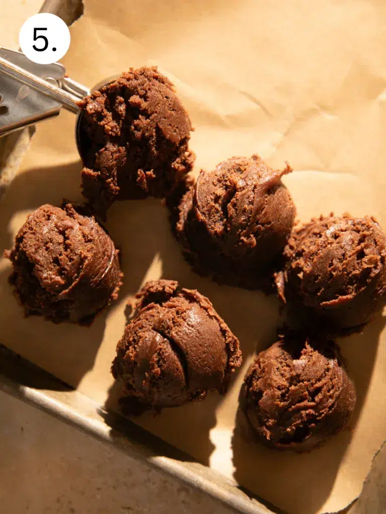 Chocolate espresso cookie dough rolled into smooth balls arranged on a baking sheet ready for baking.