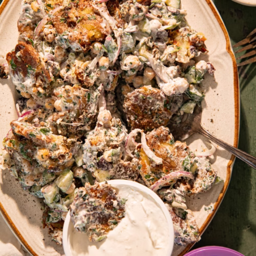 Crispy smashed Greek potato salad topped with creamy dressing and served alongside French onion sour cream dip.