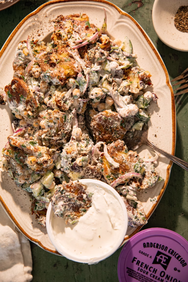 Crispy smashed Greek potato salad topped with creamy dressing and served alongside French onion sour cream dip.