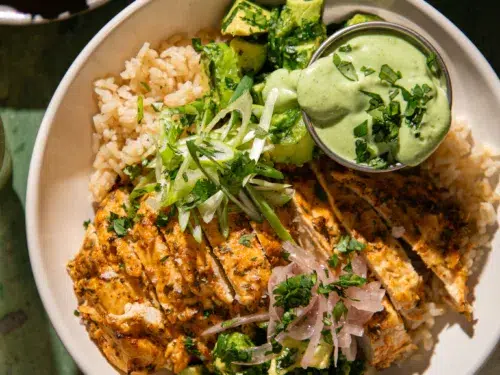 Yogurt marinated cilantro lime chicken served over rice with avocado, green onions, pickled onions, and creamy green sauce.