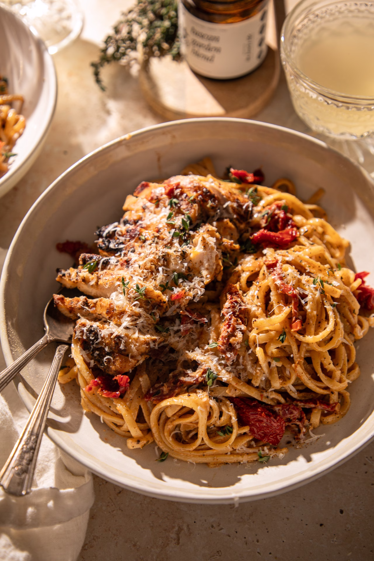 Bowl of creamy Tuscan chicken pasta with linguine, sun-dried tomatoes, parmesan cheese, and sliced seasoned chicken.