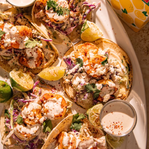 Detailed view of shrimp tacos topped with creamy sauce, cabbage slaw, and fresh cilantro