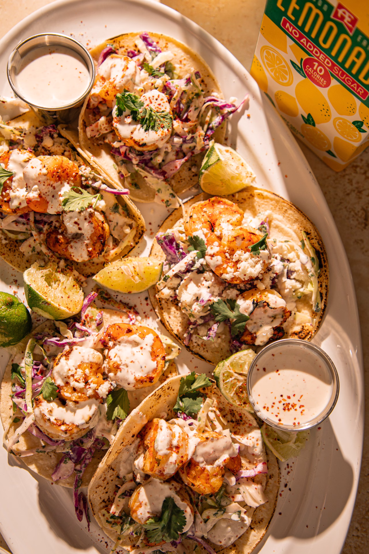 Detailed view of shrimp tacos topped with creamy sauce, cabbage slaw, and fresh cilantro