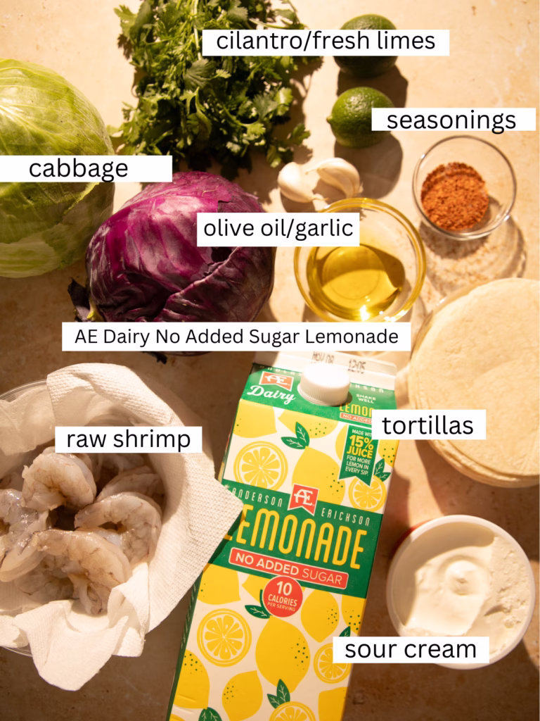 Fresh ingredients including shrimp, cabbage, cilantro, limes, tortillas, and lemonade for shrimp tacos