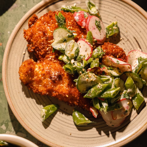 Crispy sesame chicken cutlets served with a creamy sweet pea salad made with snap peas, cucumbers, radishes, fresh herbs, and sesame seeds.