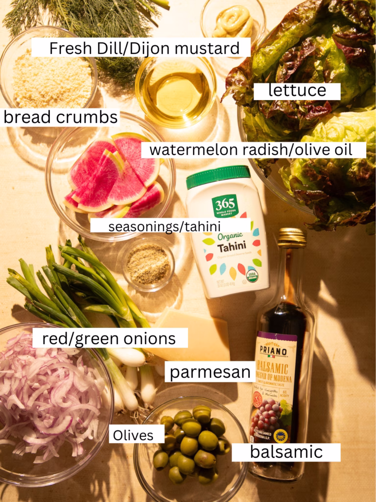 Ingredients for a little gem lettuce salad including little gem lettuce, watermelon radish, Castelvetrano olives, red onions, green onions, fresh dill, Parmesan cheese, panko breadcrumbs, tahini, Dijon mustard, olive oil, and balsamic vinegar.